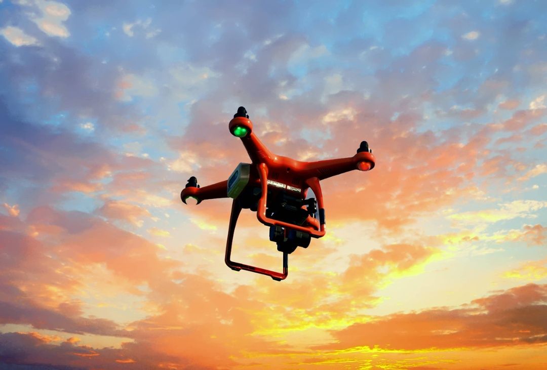red photogrammetry drone flying in front of sunset