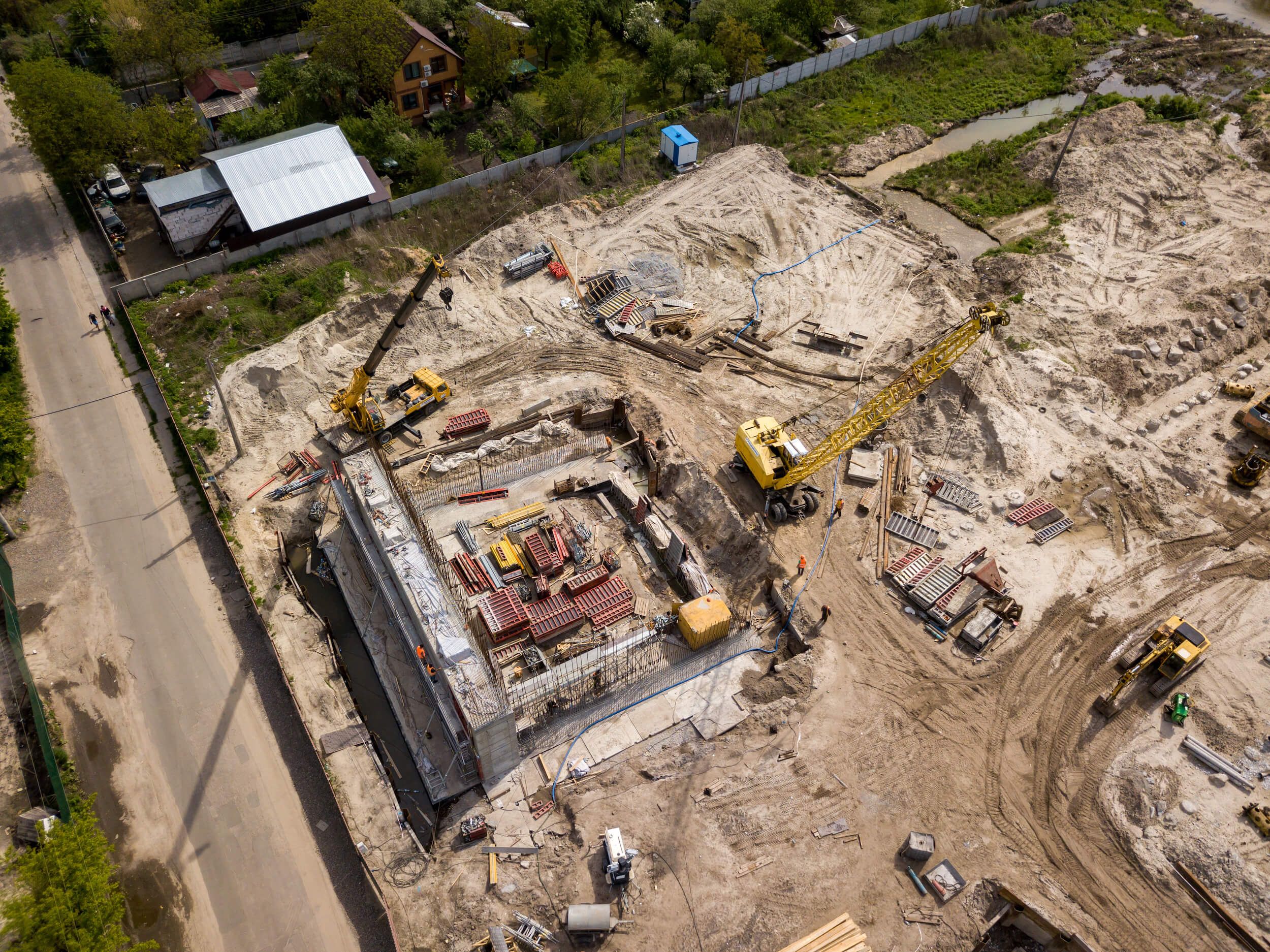 Engineering drone orthophoto of earthworks progress, building, and crane at construction site