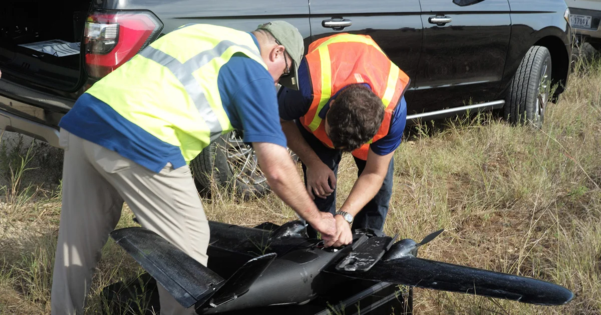 Two people working on drone in the field