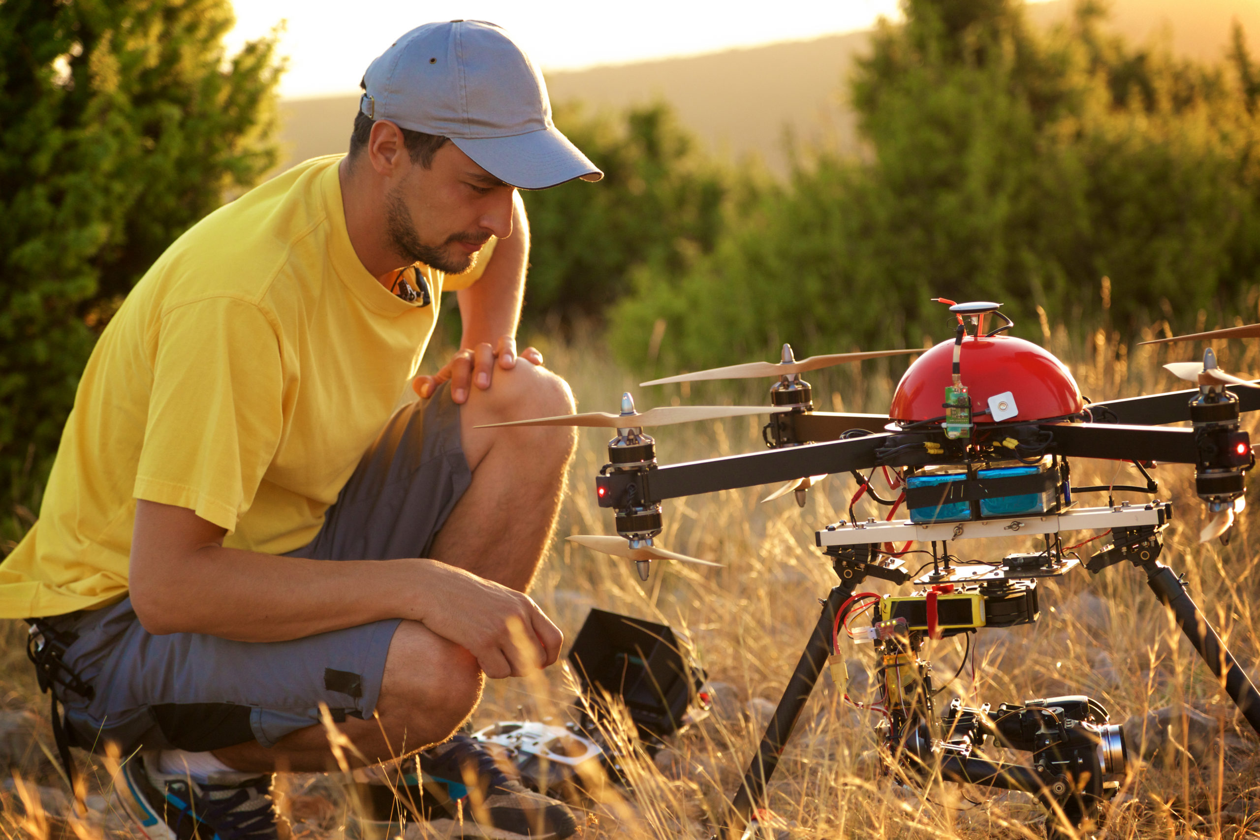 A man in a rural landscape kneeling over drone