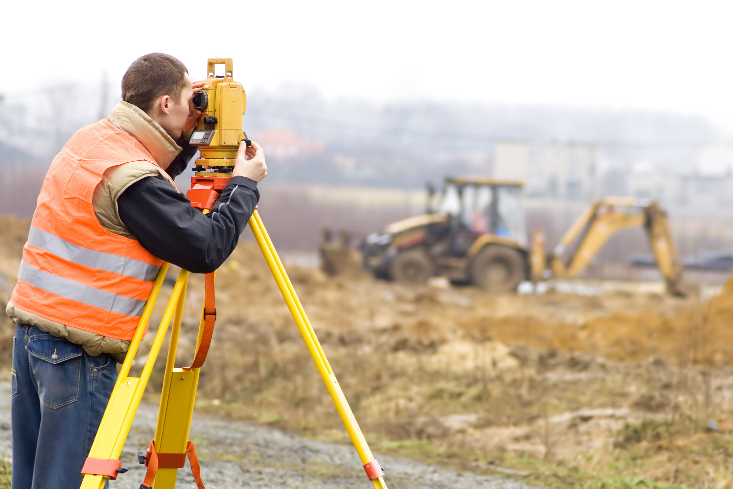 Land surveyor working with total station on a construction site (excavator is beyond depth of field)